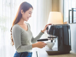 エスプレッソマシンでコーヒーを淹れる若い女性