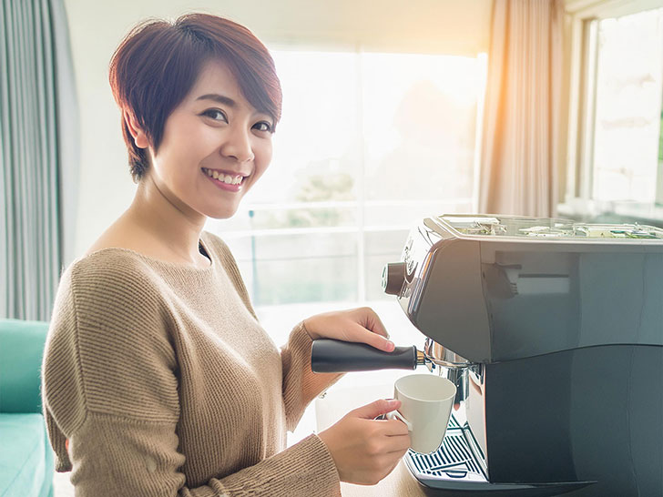 エスプレッソマシンでコーヒーを淹れる若い女性