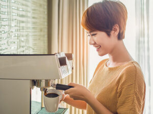 エスプレッソマシンでコーヒーを淹れる若い女性