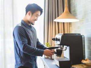 エスプレッソマシンでコーヒーを淹れる若いオシャレな男性