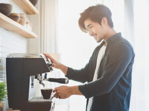 エスプレッソマシンでコーヒーを淹れる若いオシャレな男性