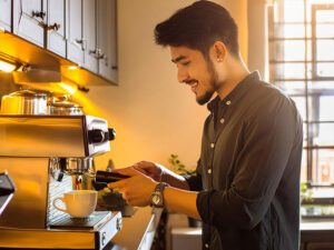 エスプレッソマシンでコーヒーを淹れる若いオシャレな男性