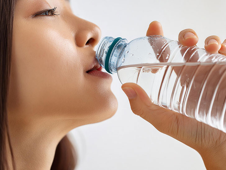 ペットボトルから水を飲む若い女性