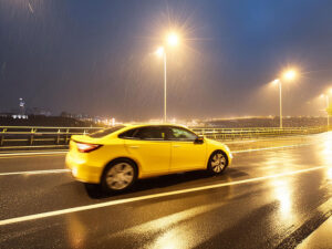 雨の道路を走る黄色い車