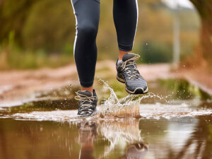 水たまりを蹴って走るスニーカーの足元