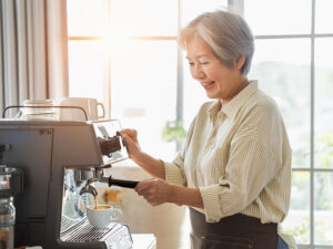 エスプレッソマシンでコーヒーを淹れるシニア女性