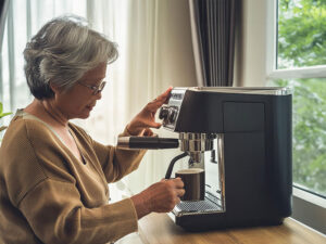 エスプレッソマシンでコーヒーを淹れるシニア女性