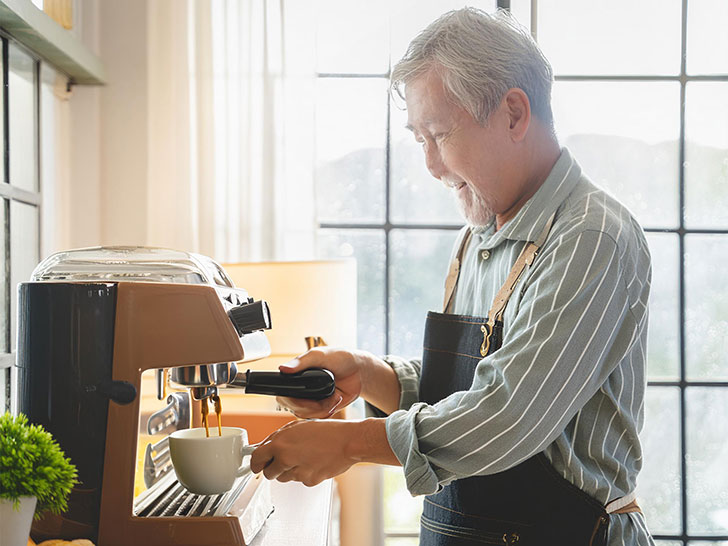 エスプレッソマシンでコーヒーを淹れるシニア男性