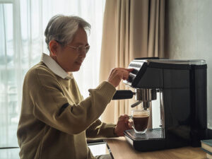 エスプレッソマシンでコーヒーを淹れるシニア男性