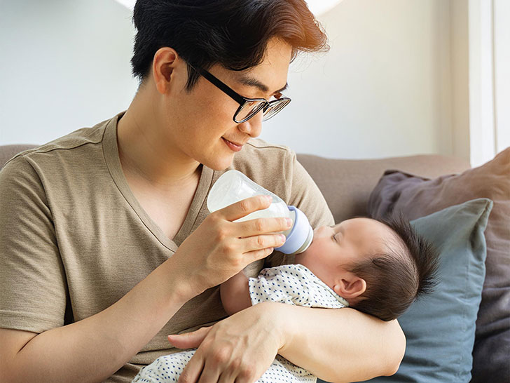 赤ちゃんにミルクをあげるお父さん