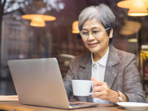 おしゃれなカフェで仕事をするシニア女性