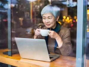 おしゃれなカフェで仕事をするシニア女性