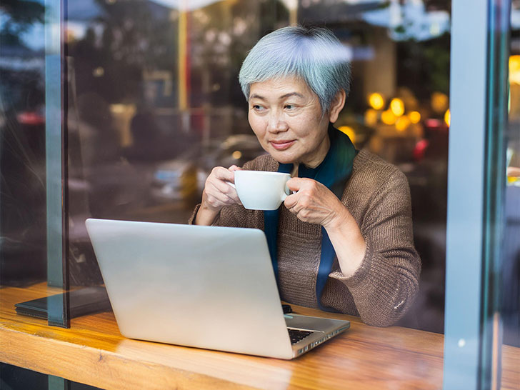 おしゃれなカフェで仕事をするシニア女性