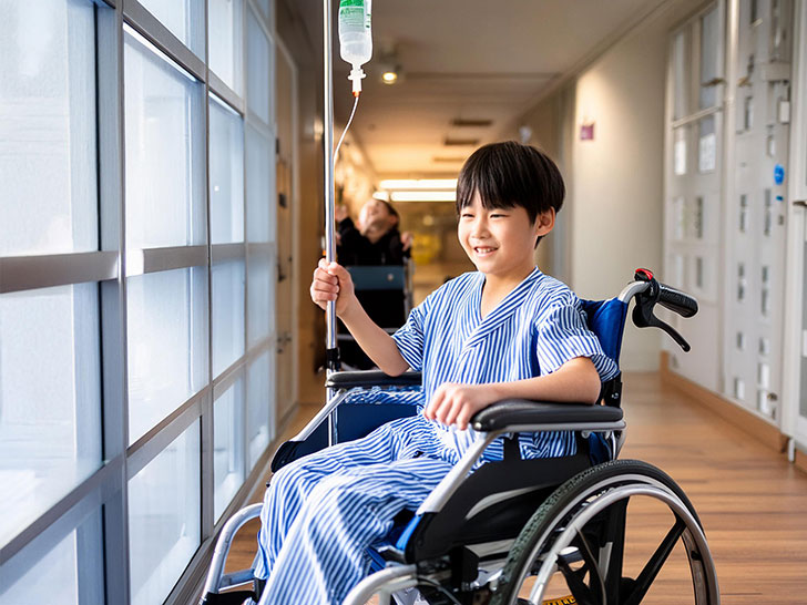 車いすに座って病院内にいる小学生の男の子