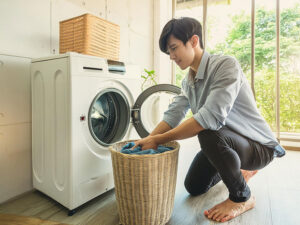 ドラム式洗濯機で洗濯をする若い男性