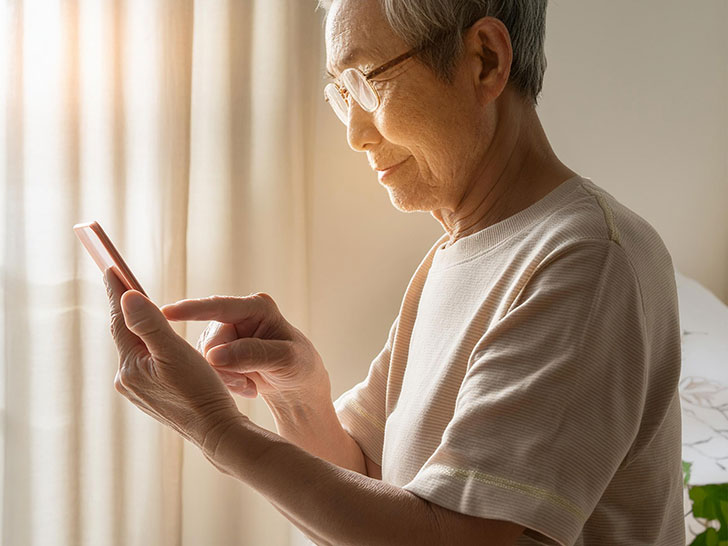 スマホを操作するTシャツ姿の高齢男性