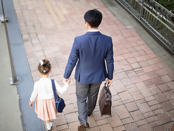 スーツを着て娘と手をつなぐ父親の後ろ姿