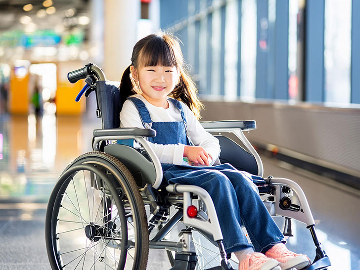 車いすで空港のロビーにいる小学生の女の子