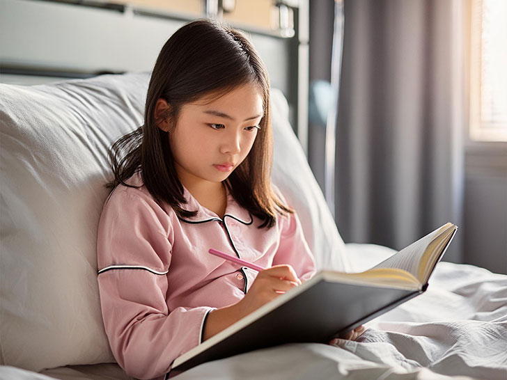 病院のベッドで勉強する小学生の女の子