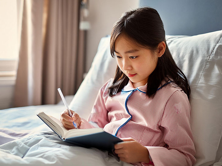 病院のベッドで勉強する小学生の女の子