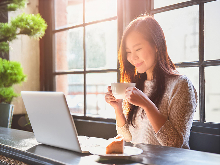 おしゃれなカフェでテレワークをする若い女性