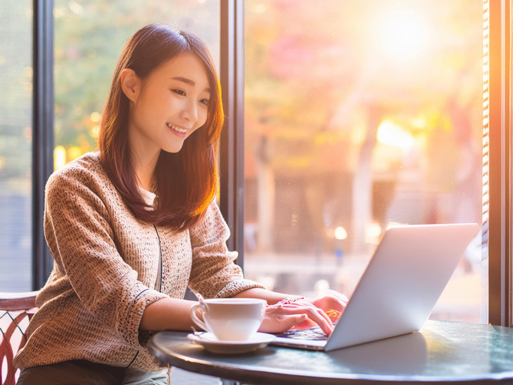 おしゃれなカフェでテレワークをする若い女性