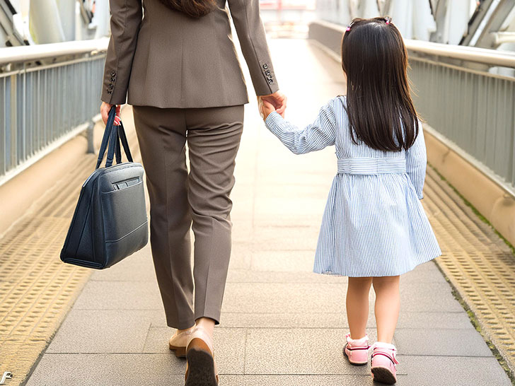 スーツを着て娘と手をつなぐ母親の後ろ姿