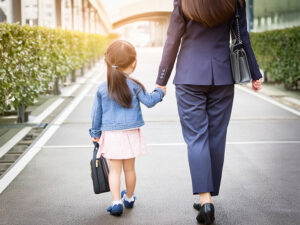 スーツを着て娘と手をつなぐ母親の後ろ姿