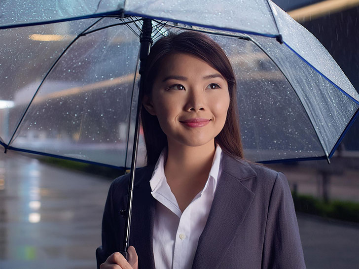 スーツを着て雨傘をさす若い女性