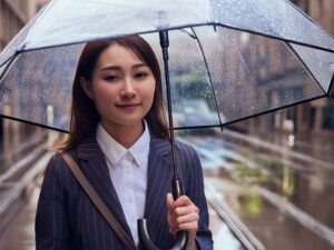 スーツを着て雨傘をさす若い女性