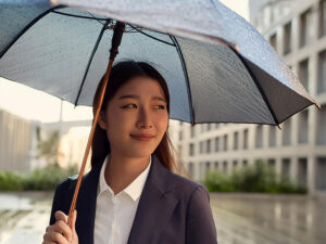 スーツを着て雨傘をさす若い女性