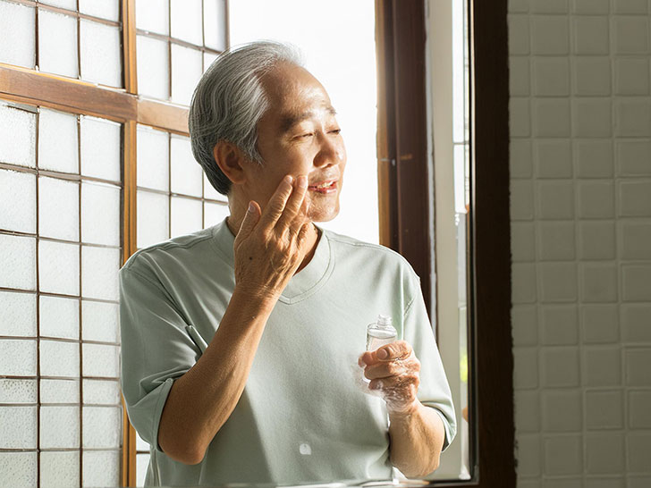 洗面所でスキンケアをする年配の男性