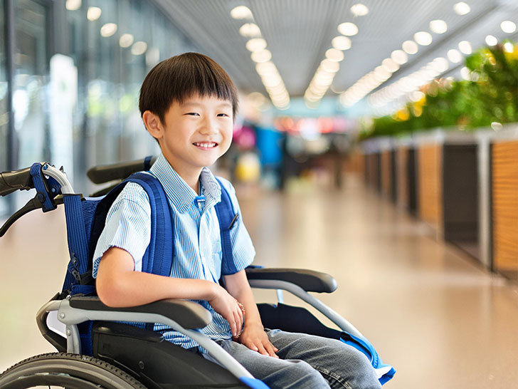 車いすで空港のロビーにいる小学生の男の子