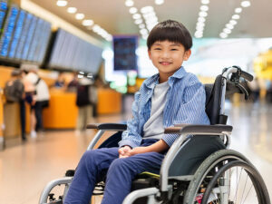 車いすで空港のロビーにいる小学生の男の子