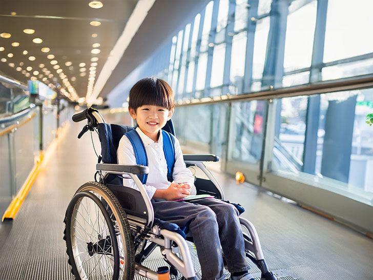 車いすで空港のロビーにいる小学生の男の子