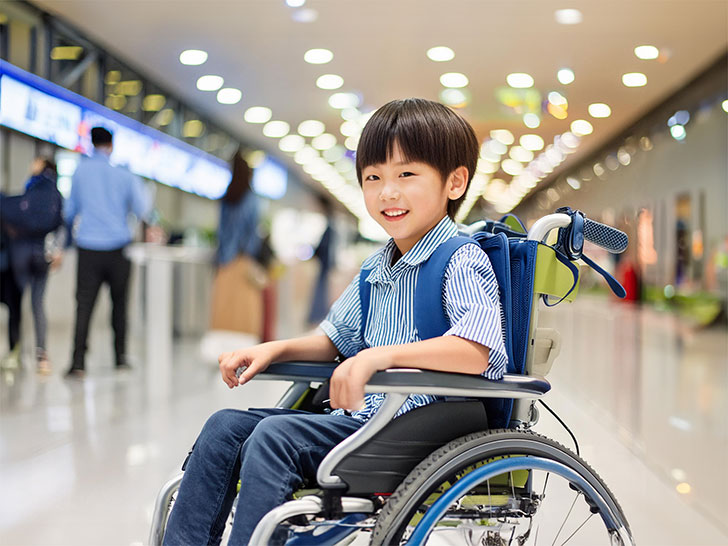 車いすで空港のロビーにいる小学生の男の子