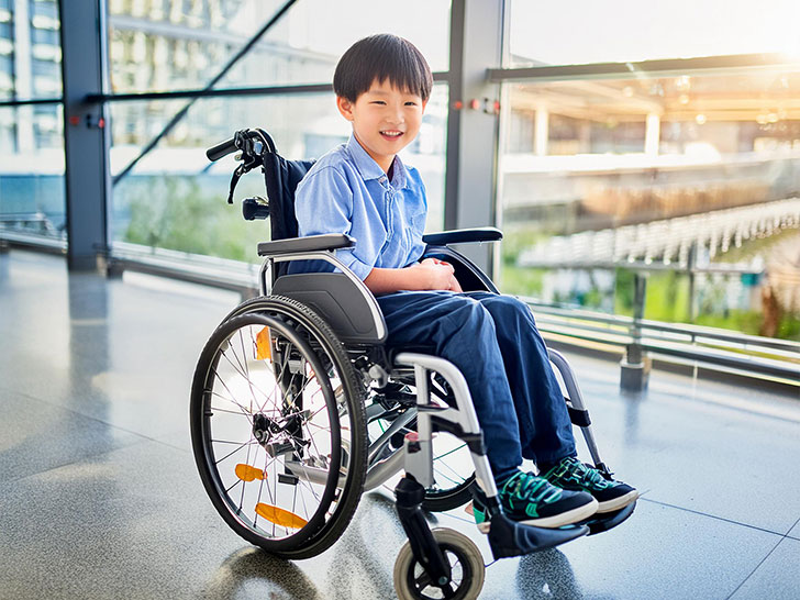 車いすで空港のロビーにいる小学生の男の子