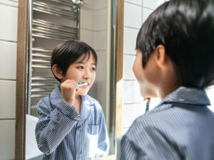 鏡の前で歯磨きをする小学生の男の子