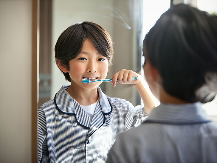 鏡の前で歯磨きをする小学生の男の子