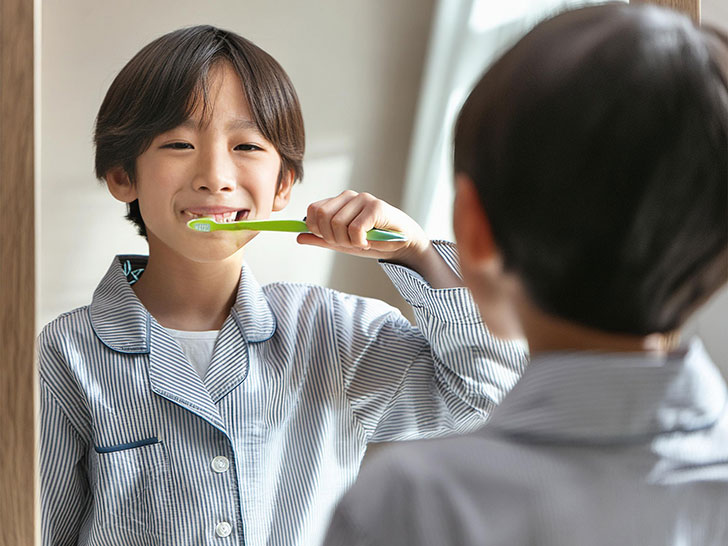 鏡の前で歯磨きをする小学生の男の子