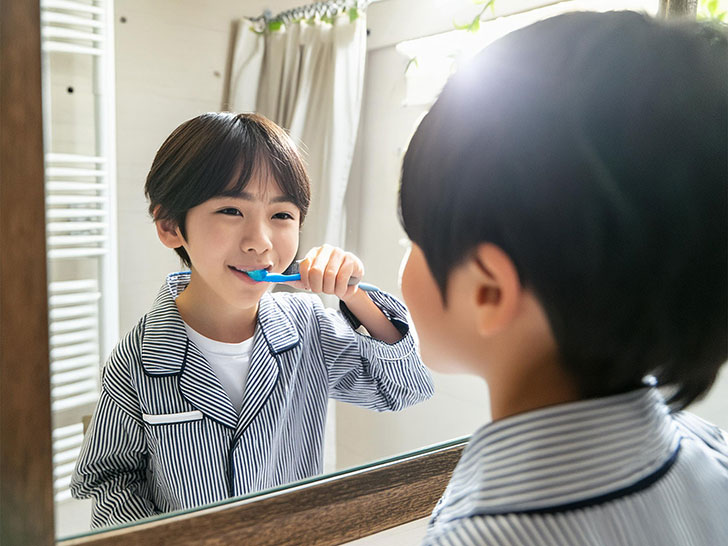 鏡の前で歯磨きをする小学生の男の子