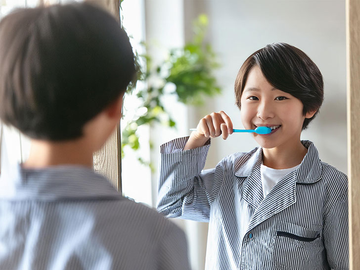 鏡の前で歯磨きをする小学生の男の子