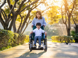 小さな息子の車椅子を押すお母さん