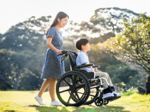 小さな息子の車椅子を押すお母さん