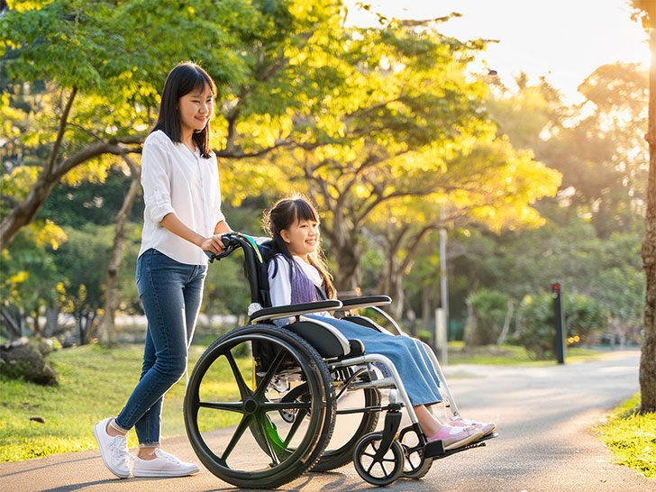 小さな娘の車椅子を押すお母さん