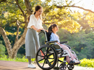 小さな娘の車椅子を押すお母さん