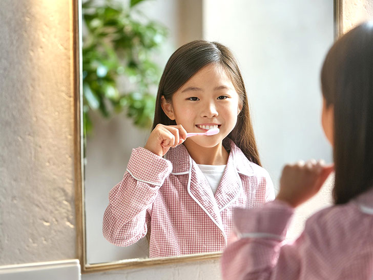 鏡の前で歯磨きをする小学生の女の子