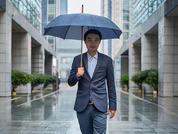 スーツを着て雨傘をさす若い男性