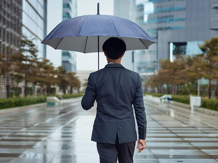 スーツを着て雨傘をさす若い男性