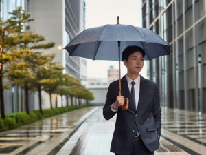 スーツを着て雨傘をさす若い男性